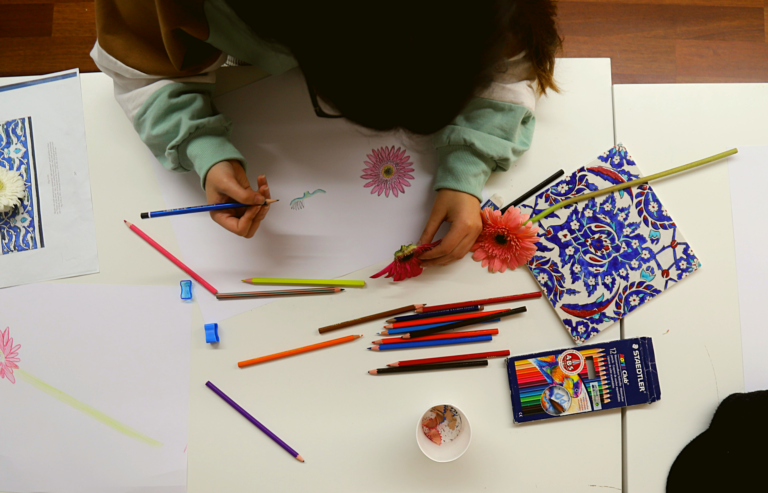 A young Syrian refugee uses colored pencils to draw flowers.